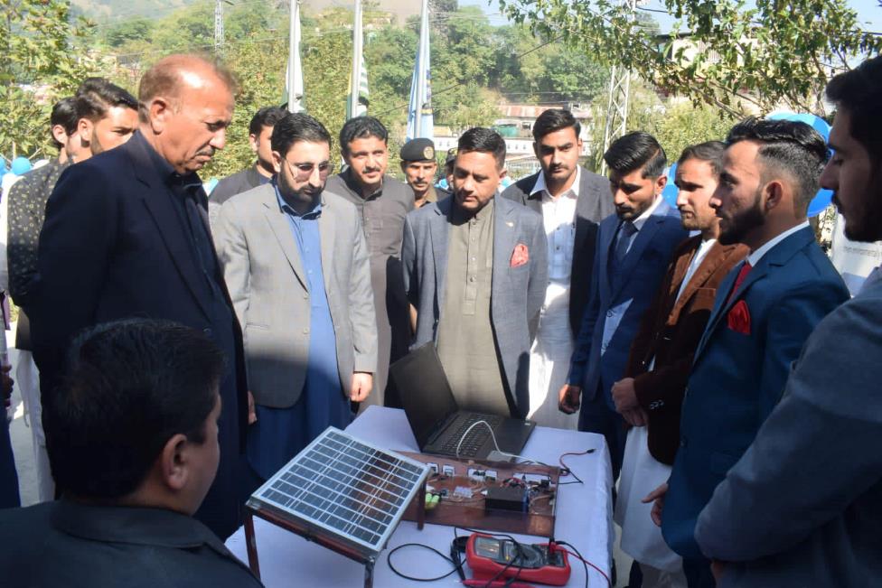 A group of men standing around a table with a solar panel

Description automatically generated